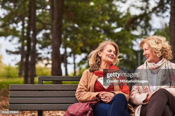 two senoir woman talking - fall park stock pictures, royalty-free photos & images