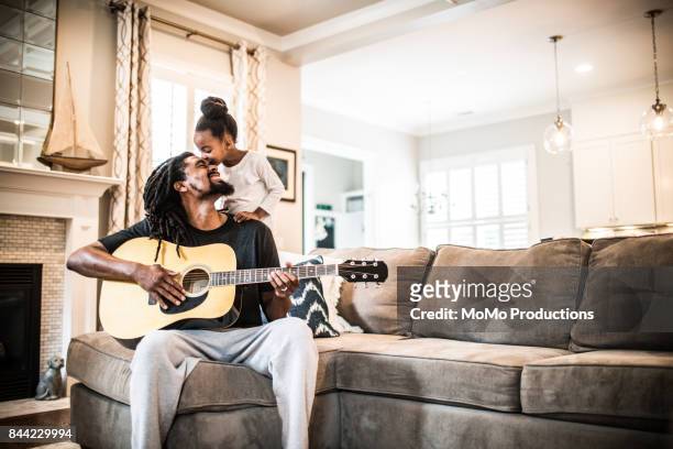 father playing guitar with children near - living room family happiness stock pictures, royalty-free photos & images