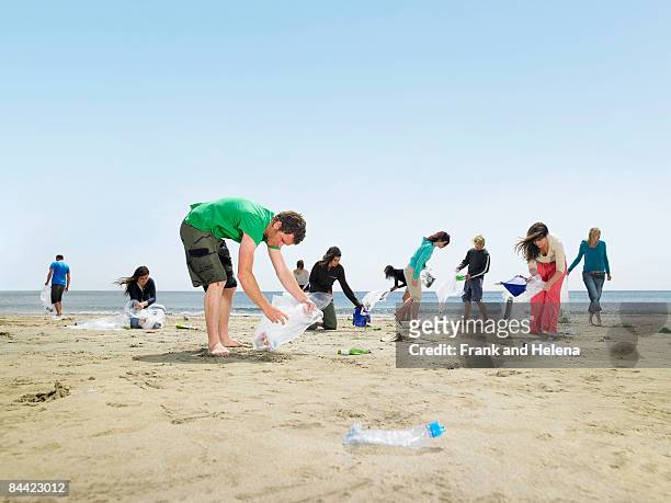 young people collecting garbage on beach - volunteer beach photos et images de collection