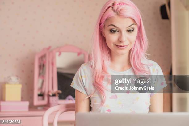 mujer joven con el pelo teñido de rosa blogging portátil en dormitorio - dyed red hair fotografías e imágenes de stock