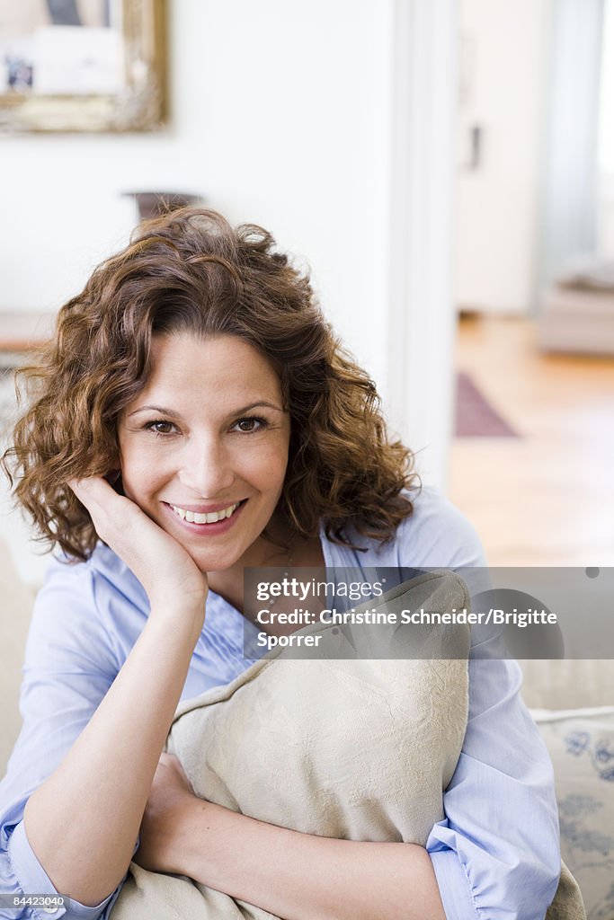 Woman hugging pillow sitting on a couch