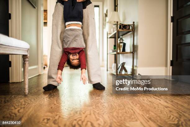 father holding toddler son upside down - quirky family stock-fotos und bilder