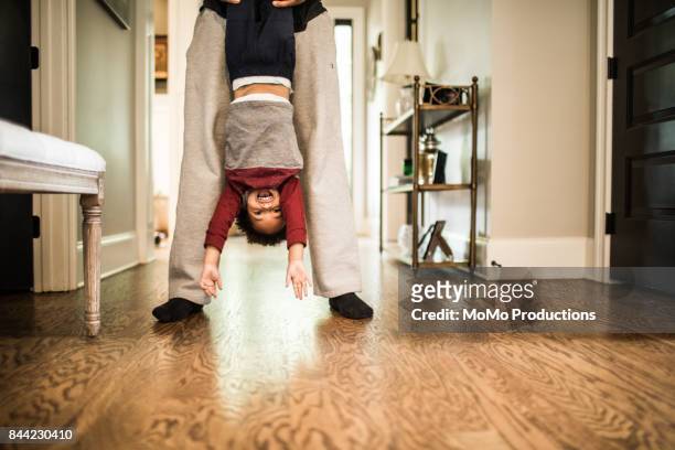 father holding toddler son upside down - quirky family stockfoto's en -beelden