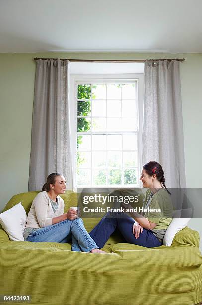 two young women on couch, with mugs - family on couch with mugs stock pictures, royalty-free photos & images