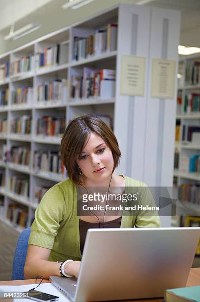 young woman working on laptop in library - mp3 speler stock pictures, royalty-free photos & images