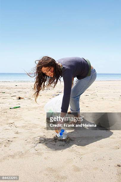 young girl collecting garbage on beach - hole stock-fotos und bilder