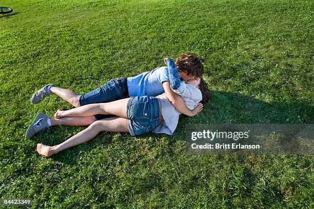 teen couple laying on grass, kissing - teenagers kissing stock pictures, royalty-free photos & images
