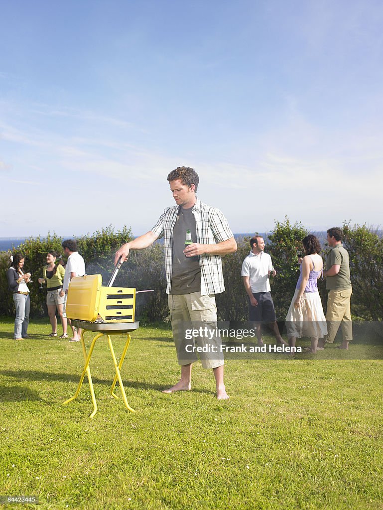 Man tending barbecue at a party