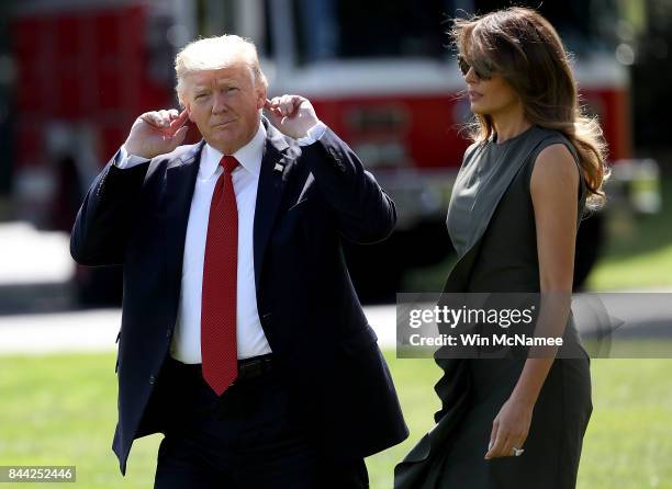 President Donald Trump, accompanied by first lady Melania Trump, points to his ears as he tries to hear shouted questions from reporters while...