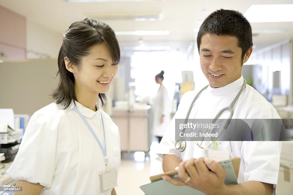 Japanese doctor and nurse looking at clipboard