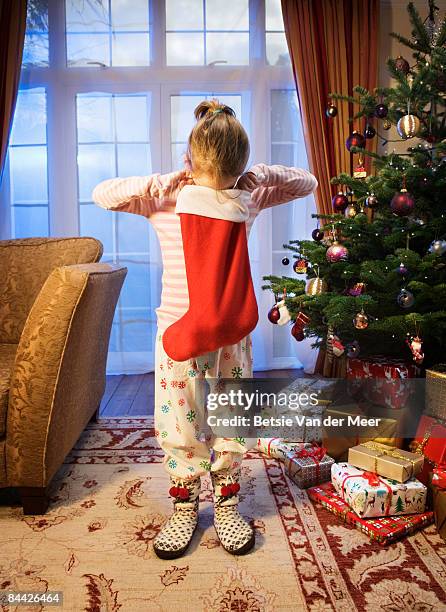 girl looking in christmas stocking. - calza della befana foto e immagini stock