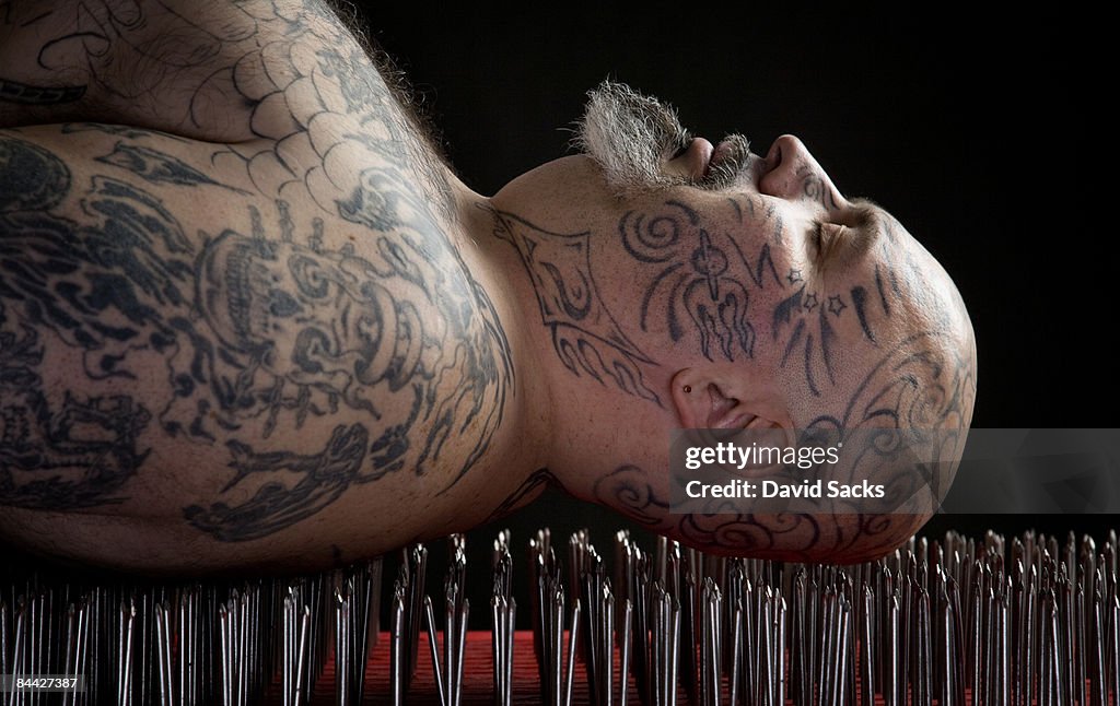 Man lying on a bed of nails.