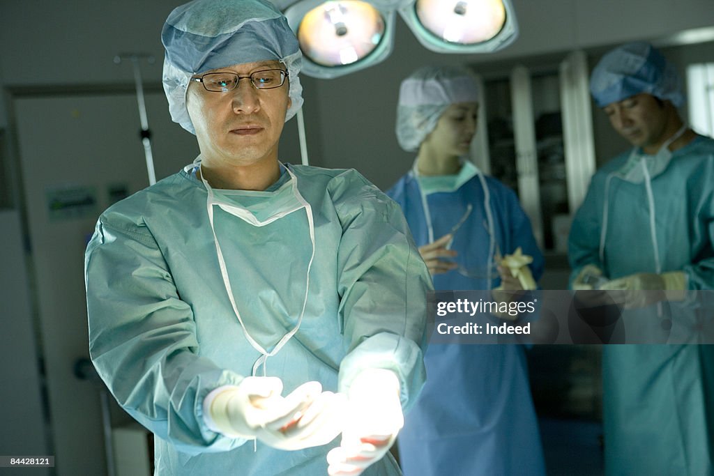 Male surgeon removing surgical glove