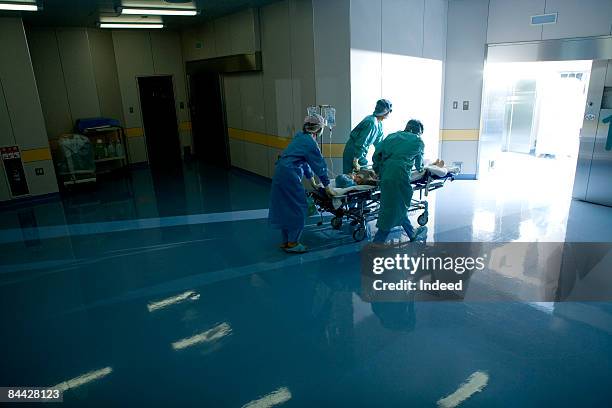 doctors pushing patient on trolley to surgent room - stretcher photos et images de collection