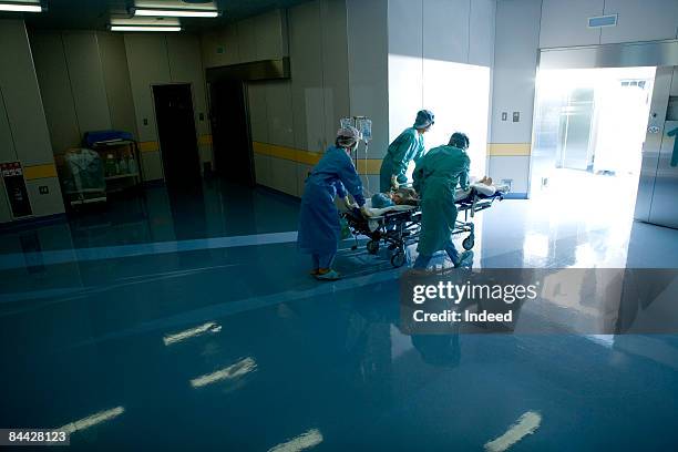 doctors pushing patient on trolley to surgent room - entering hospital stock pictures, royalty-free photos & images