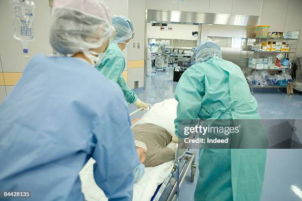 doctors pushing patient on trolley, rear view - stretcher ストックフォトと画像