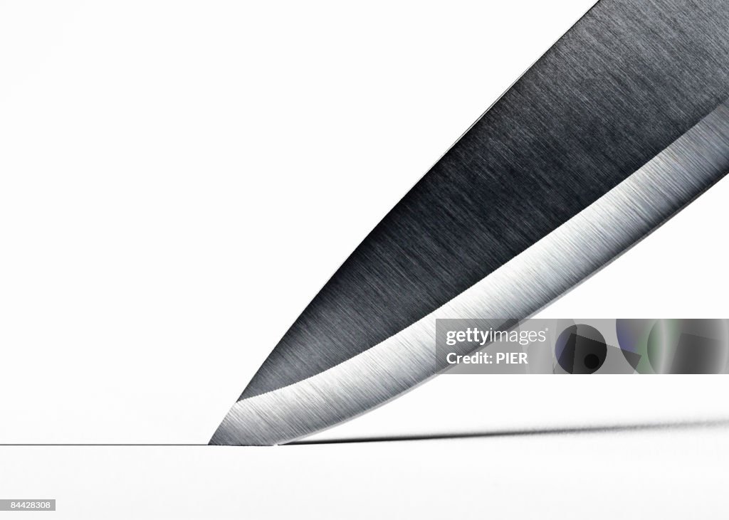 Steel knife blade cutting into surface