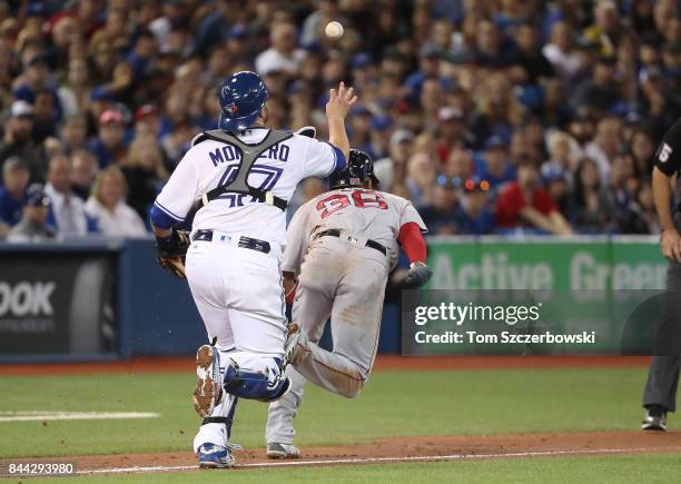 Miguel Montero of the Toronto Blue Jays makes an errant throw in a run-down allowing Eduardo Nunez of the Boston Red Sox to get back to third base...