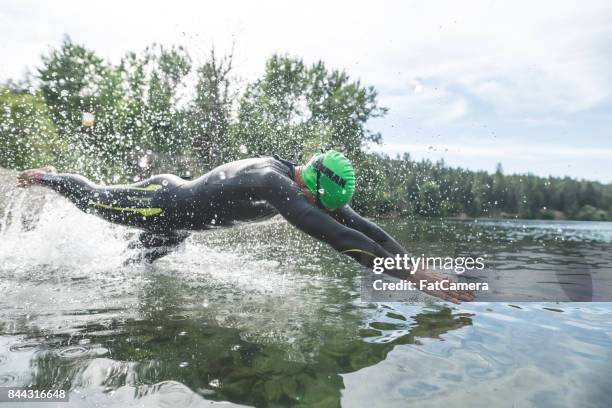 male triathlon athlete diving into the water - triathlon stock pictures, royalty-free photos & images