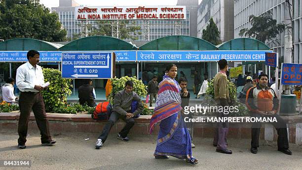 An Indian woman walks past men sitting on a kerb outside the All India Institute of Medical Sciences building, where Indian Prime Minister Manmohan...