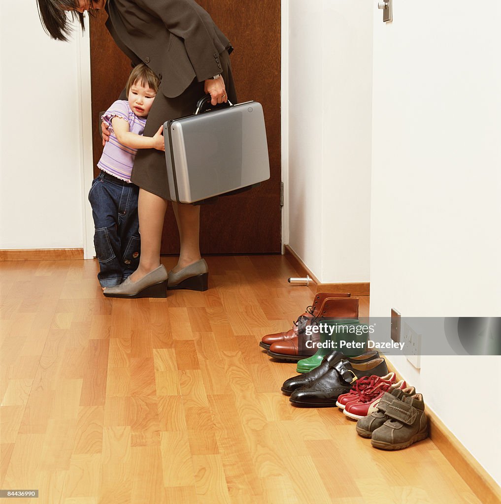 Mother leaving for work with child clinging on.