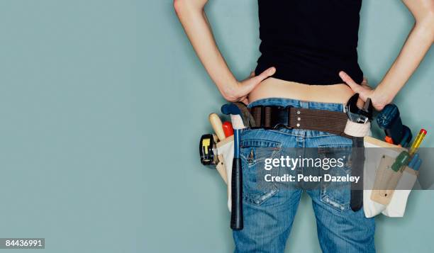 young woman wearing tool belt - werkzeug stock-fotos und bilder
