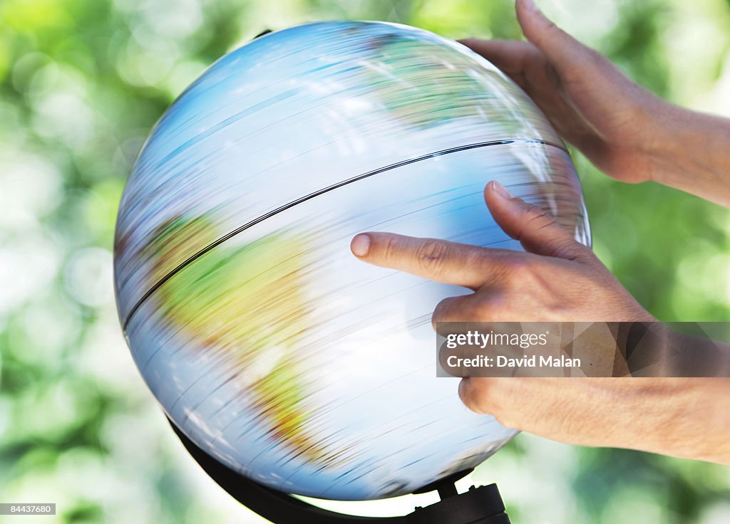 Man spining and pointing at a globe