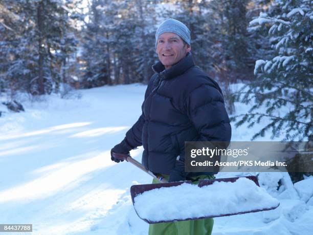 man shovels driveway snow on cold day - shoveling snow stock pictures, royalty-free photos & images