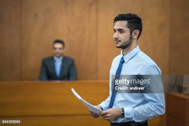 lawyer holding documents in the courtroom - legal defense stock pictures, royalty-free photos & images