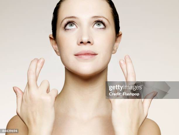 portrait of woman with her fingers crossed - fingers crossed stock pictures, royalty-free photos & images