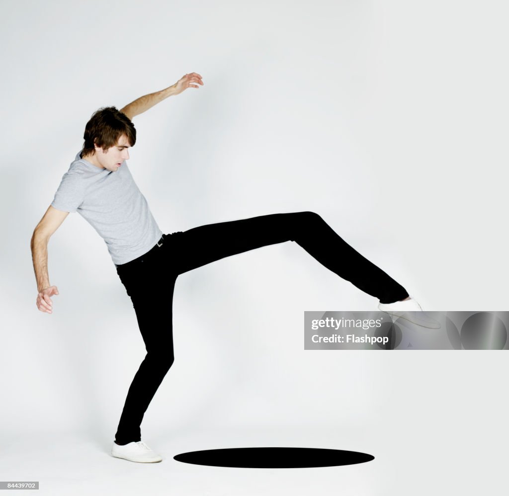 Man stretching leg to step over black hole