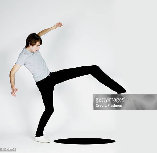 man stretching leg to step over black hole - tree on white stockfoto's en -beelden