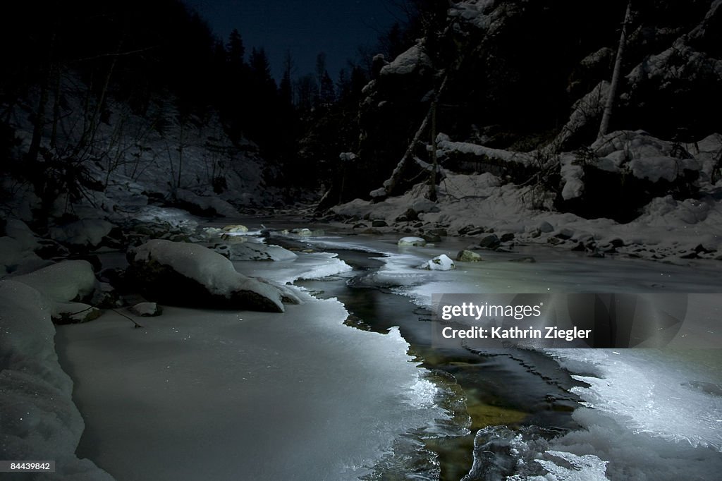 Frozen stream in snowy scenery at night