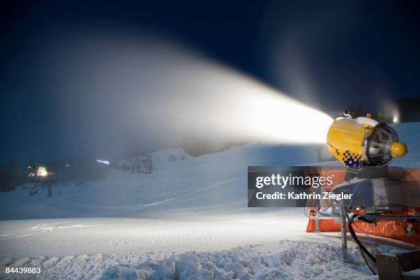 snow cannon producing artificial snow at night - sneeuwmachine stockfoto's en -beelden