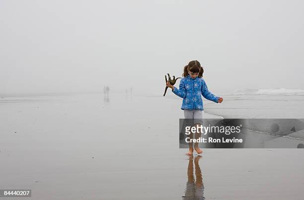 young girl walking along beach in a morning mist - man mist beach stock-fotos und bilder