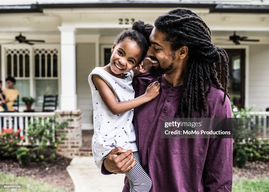 Portrait of father and daughter in front of home