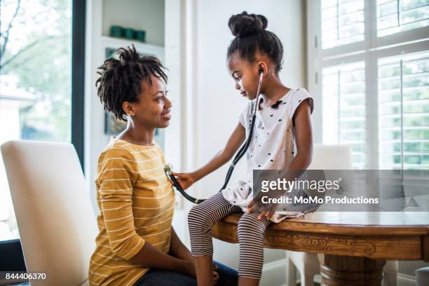daughter using stethoscope on mother - saving for the future stockfoto's en -beelden