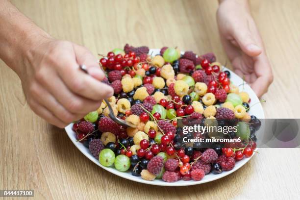 eating healthy food, summer berry fruits on white plate - frambuesa americana fotografías e imágenes de stock