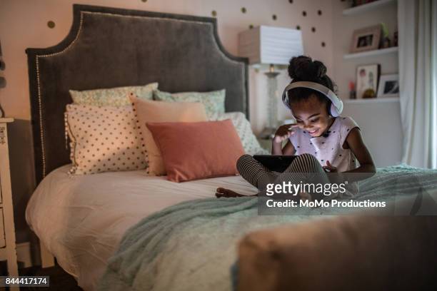 young girl (6yrs) on couch using tablet - child tablet stock pictures, royalty-free photos & images