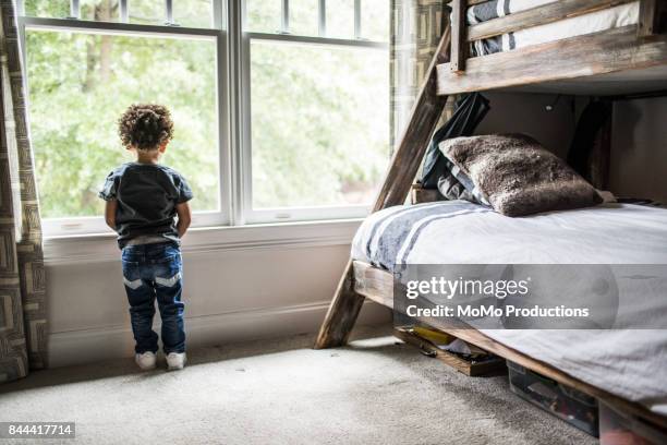 young boy (2yrs) looking out window - bunk beds for 3 stock-fotos und bilder