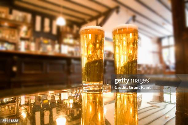 two beers sitting on table - british pub stock-fotos und bilder