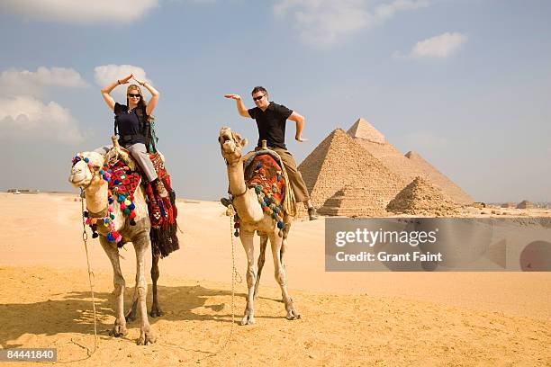 young couple having fun on camel near pyramids - portrait playful caucasian man foto e immagini stock