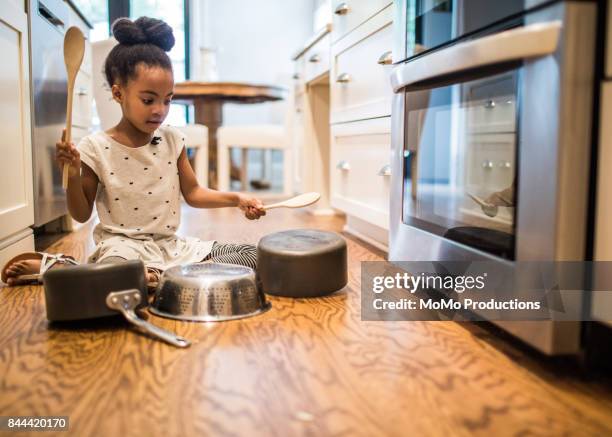 young girl (6yrs) drumming on pots and pans in kitchen - drum percussion instrument stock-fotos und bilder