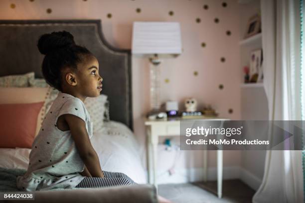 girl 4yrs) sitting on bed looking out window - girl in her bed stockfoto's en -beelden