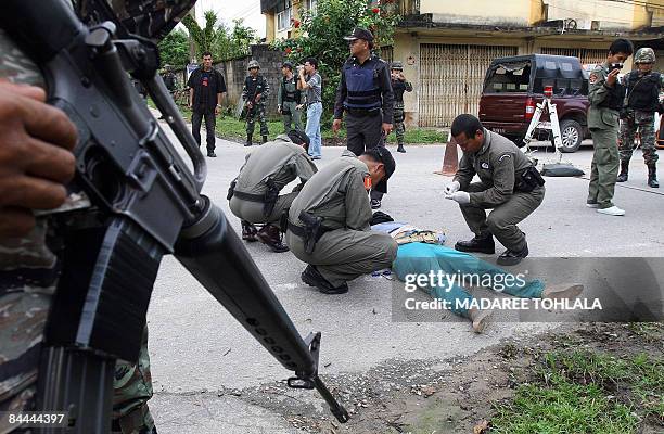 Thai policemen inspect the body of a suspected Muslim militant killed in a clash with Thai border police in Cha Nea district in Thailand's restive...