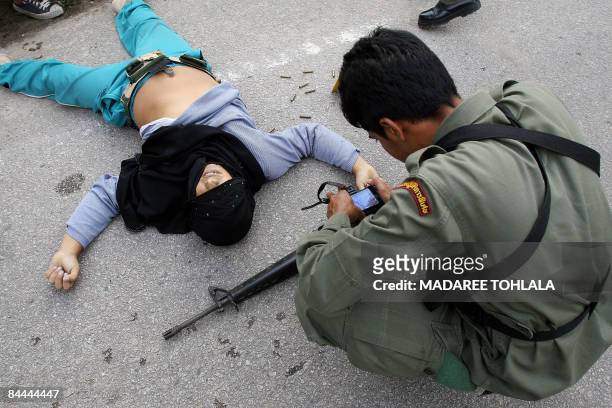Thai policeman inspects the body of a suspected Muslim militant killed in a clash with Thai border police in Cha Nea district in Thailand's restive...