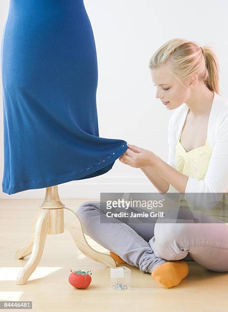 young woman pinning dress on body form - mannequin blonde stockfoto's en -beelden