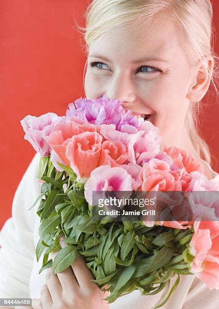 young woman holding flowers close to her - close up of flower bouquet stock-fotos und bilder