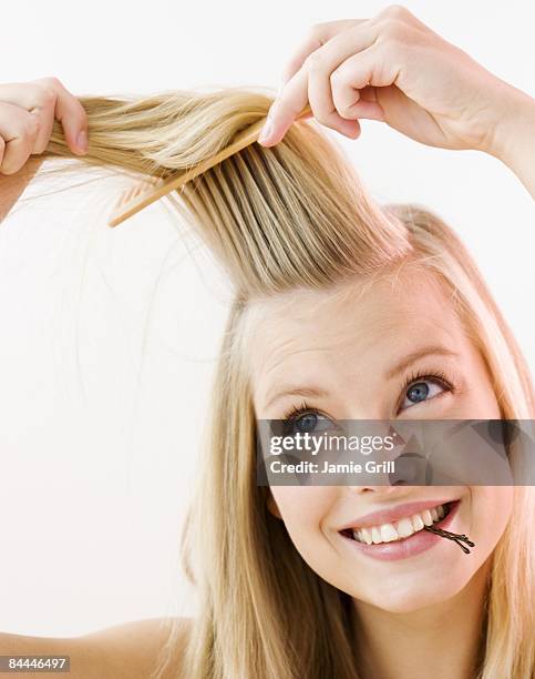 young woman brushing and styling her hair - pick foto e immagini stock