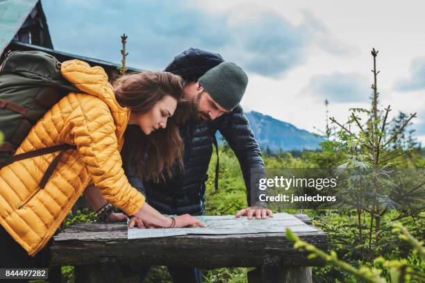 young couple planning their trip with map - wilderness map stock pictures, royalty-free photos & images